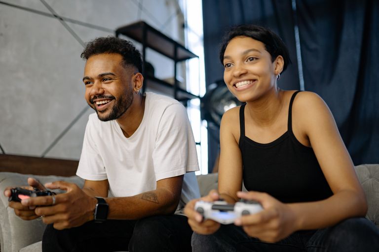 Best games to play in 2026 — a couple playing video games together on a sofa with controllers