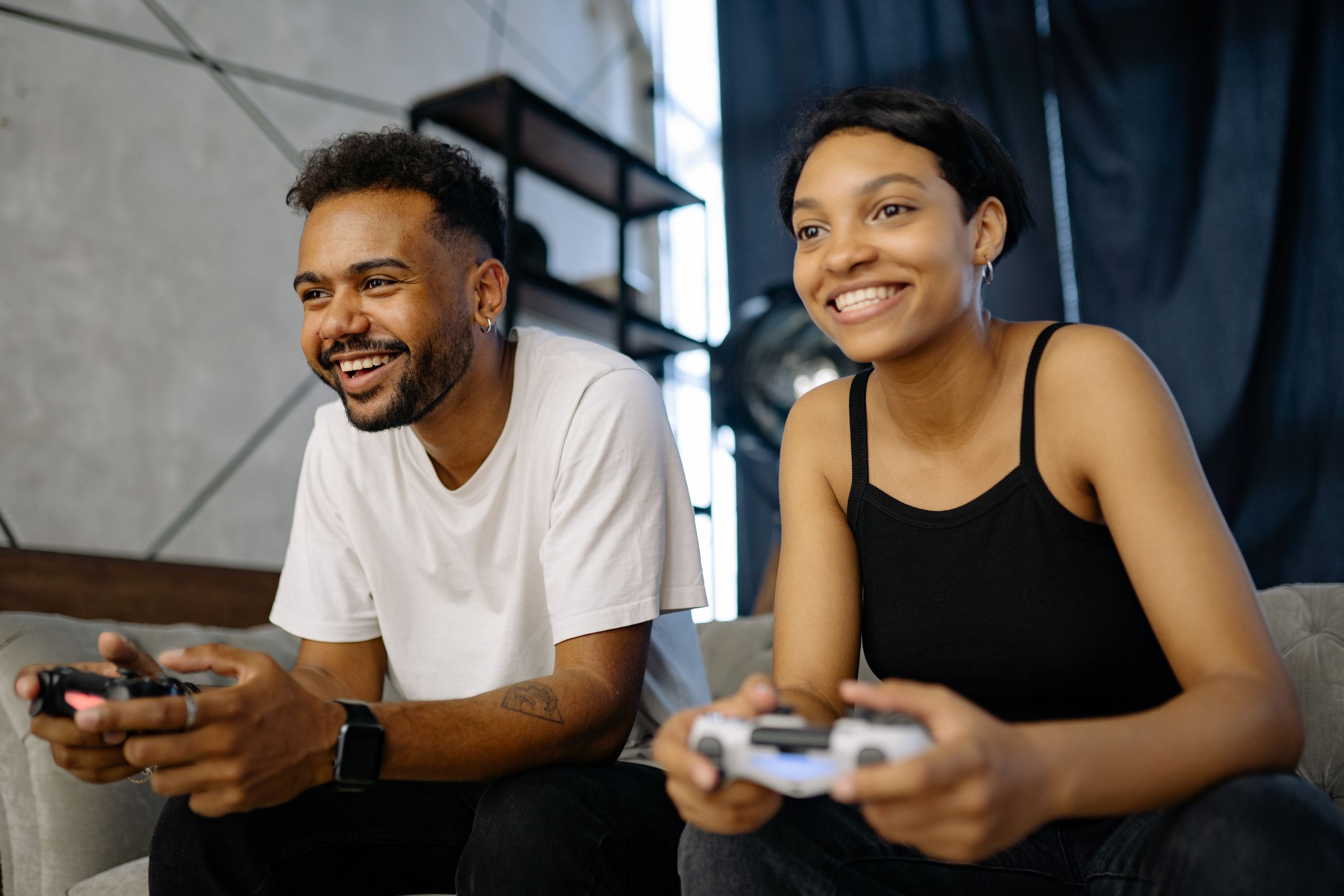 Best games to play in 2026 — a couple playing video games together on a sofa with controllers