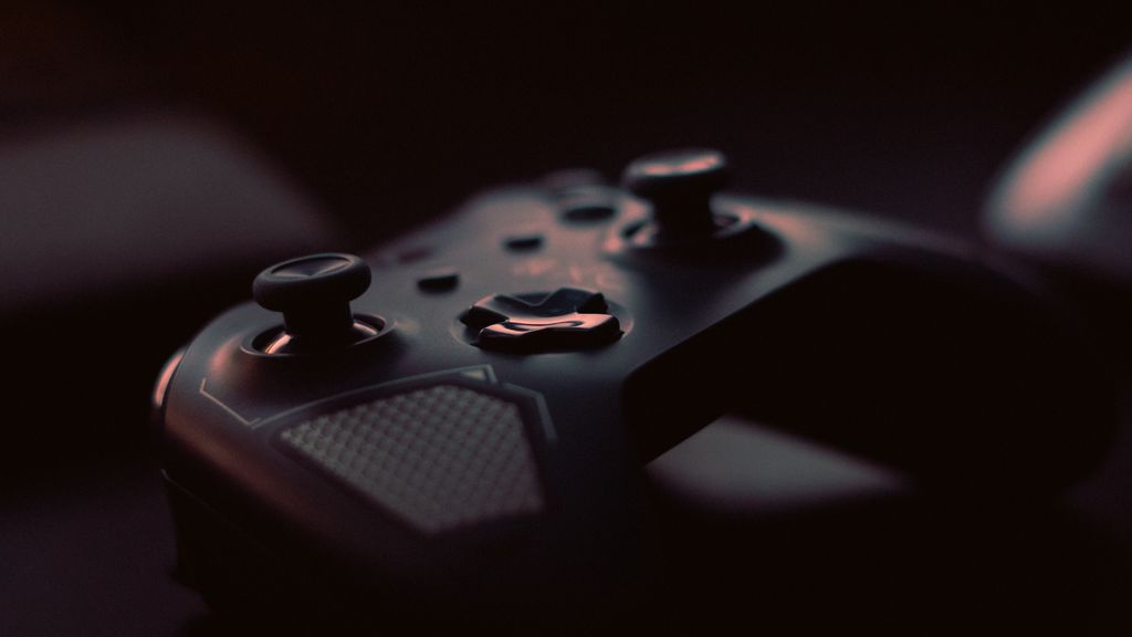 Close-up of a modern game controller in low light, highlighting its design and buttons