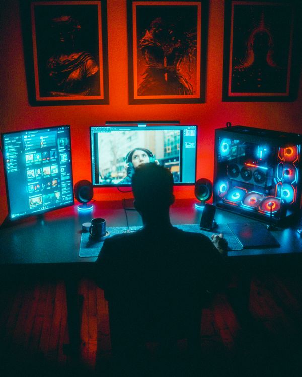 Gamer seated at a compact dual-monitor gaming desk setup at night