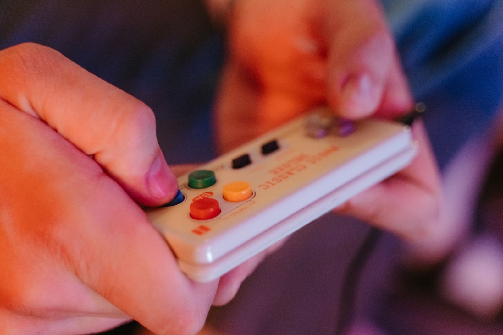 Hands holding a colorful retro game controller