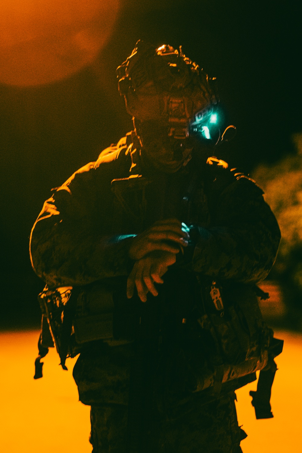 A soldier in full tactical gear with night-vision optics photographed during a nighttime operation