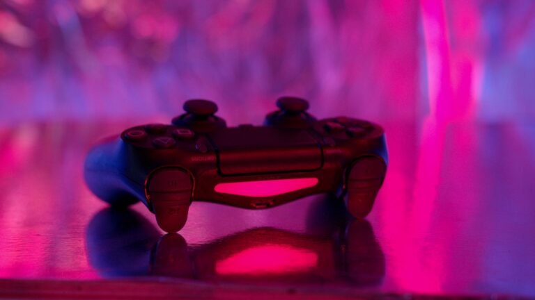 A wireless game controller in focus with a vibrant neon background