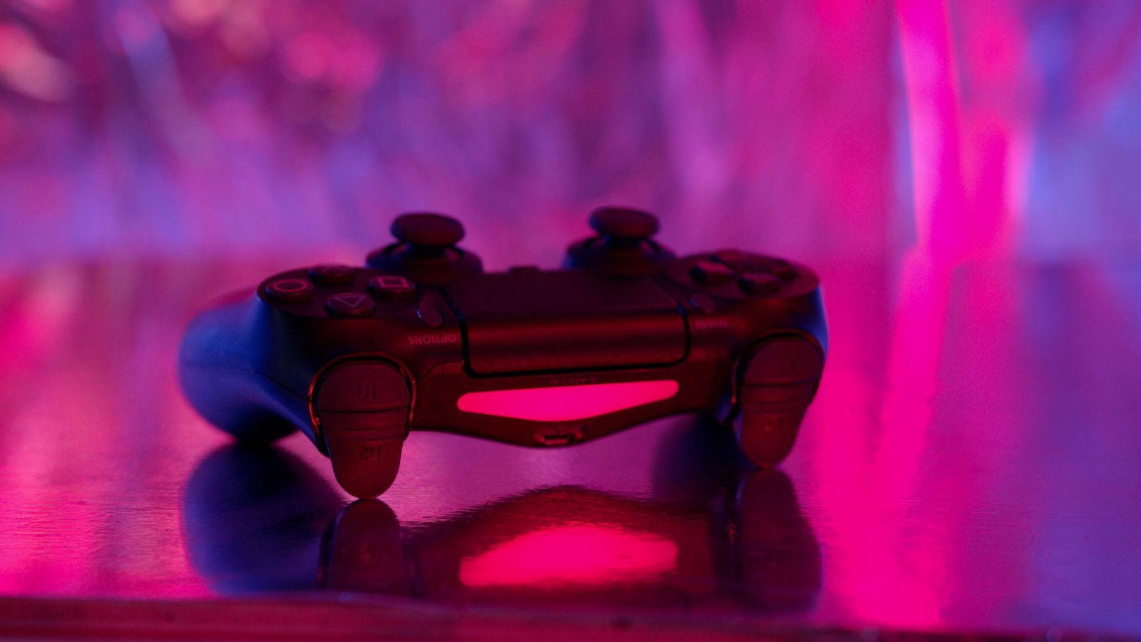 A wireless game controller in focus with a vibrant neon background