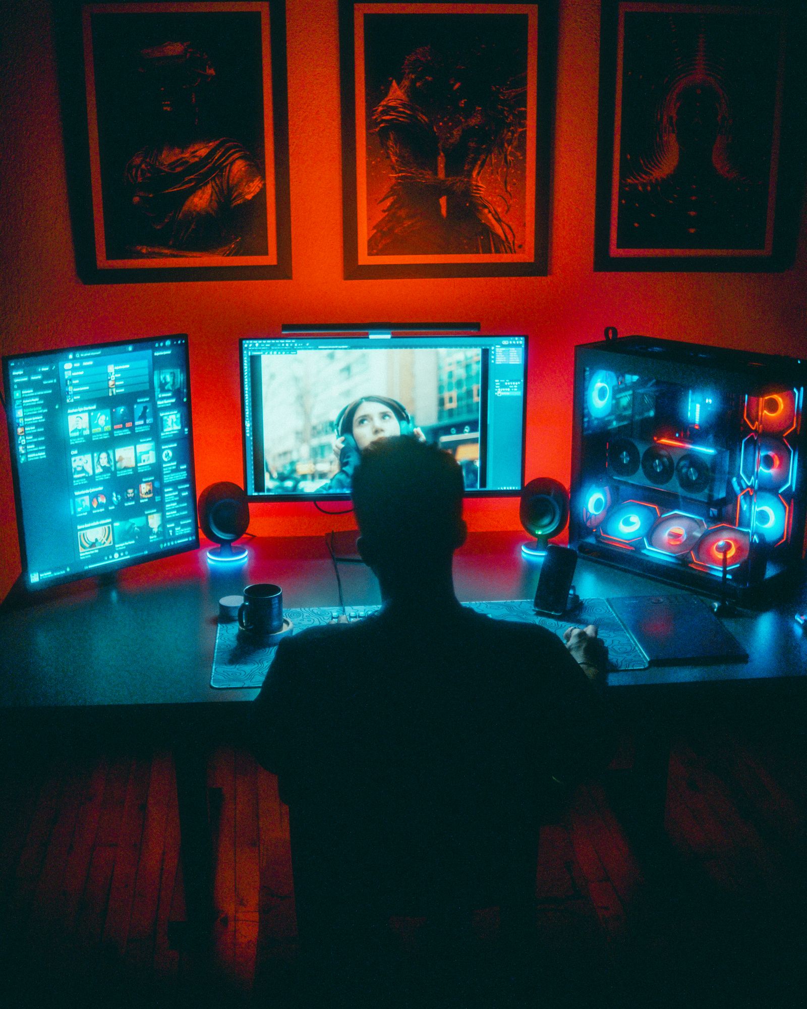 A gamer immersed in a vibrant RGB PC setup with dual monitors at night
